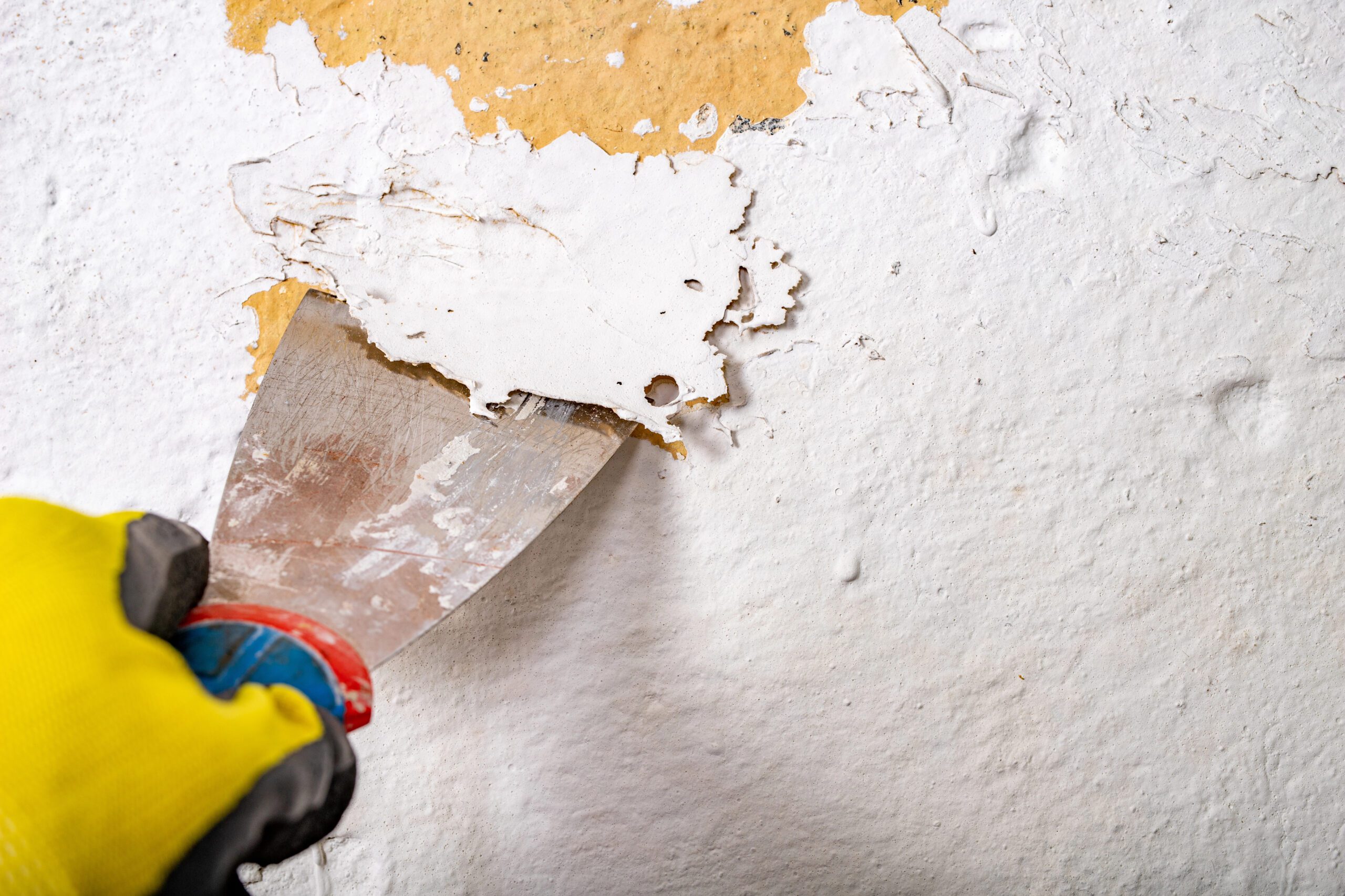 Scraping peeling lead-based paint off a wall