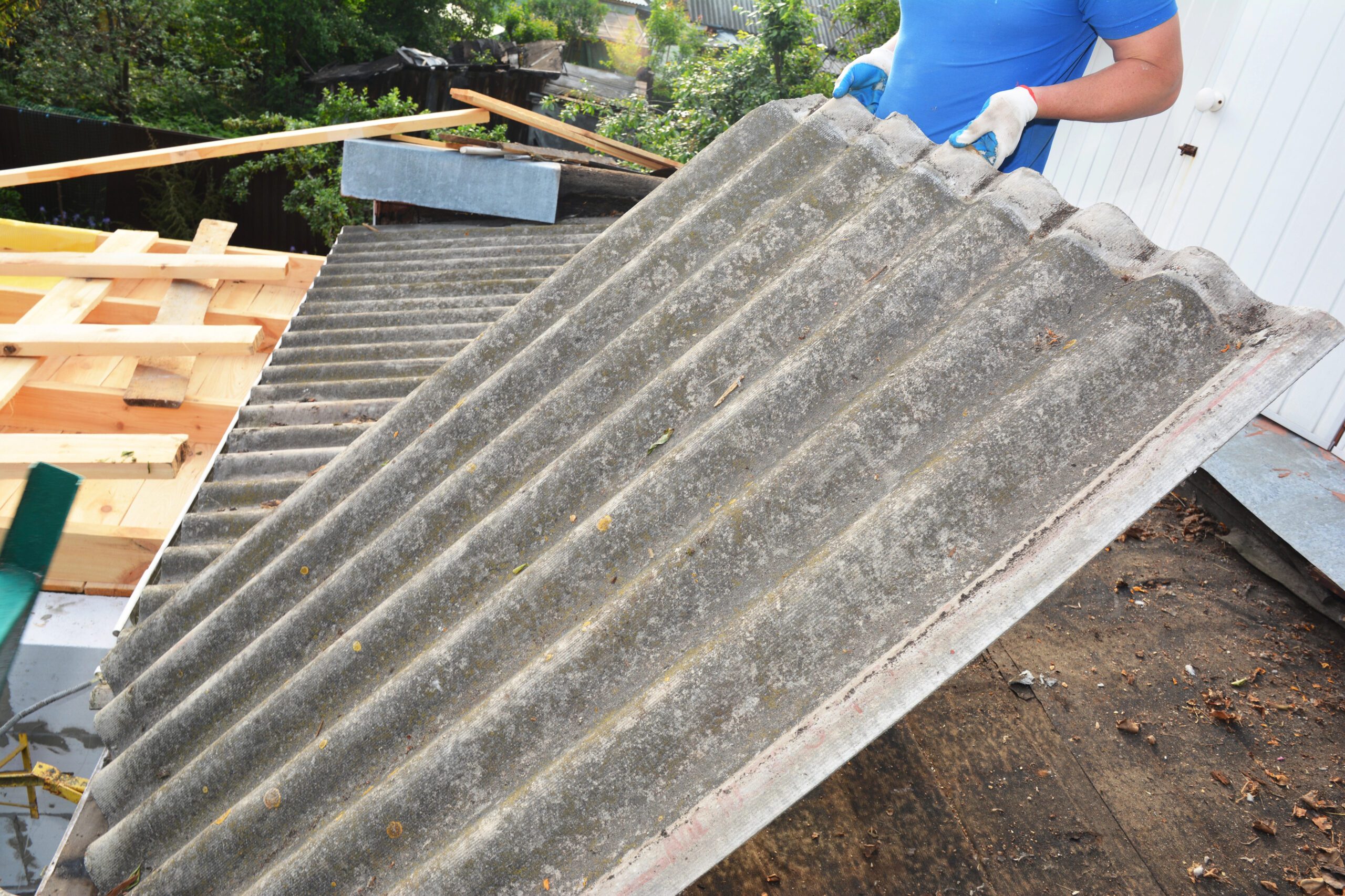Worker in gloves lifting a corrugated asbestos cement roof panel